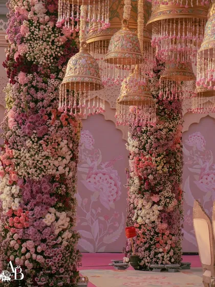 Intricate hand-painted bells hang from the ceiling of this pastel floral mandap. These bespoke details add a layer of artistry and personalization to our wedding designs.