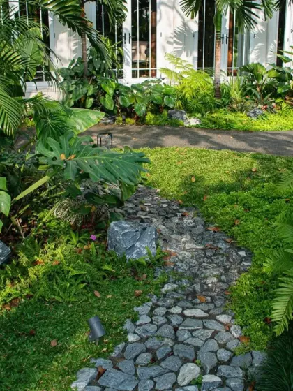 A naturalistic cobblestone path winds through a densely planted garden. This type of path is perfect for creating a rustic, cottage-garden feel.
