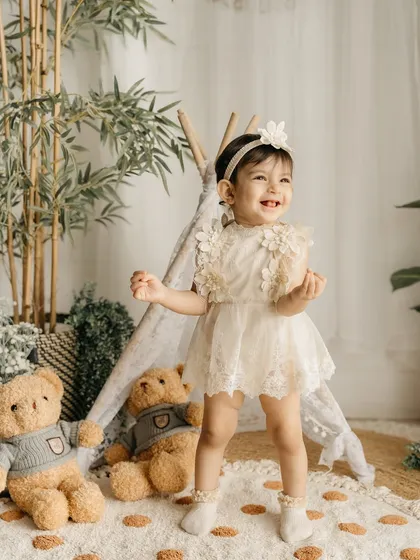 A joyful, laughing toddler in my boho-themed studio setup, complete with a teepee and teddy bears.