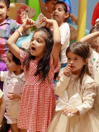 A group of girls singing and dancing along with the entertainment at a birthday party.