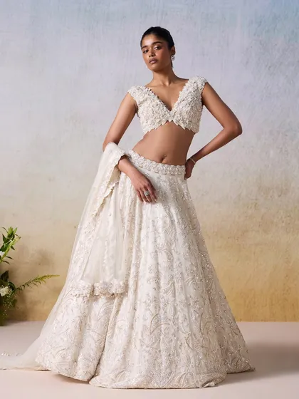 An ivory and gold lehenga that exudes timeless elegance. The hand-embroidered details and classic silhouette make this a perfect choice for a bride seeking understated luxury for her wedding day or reception.