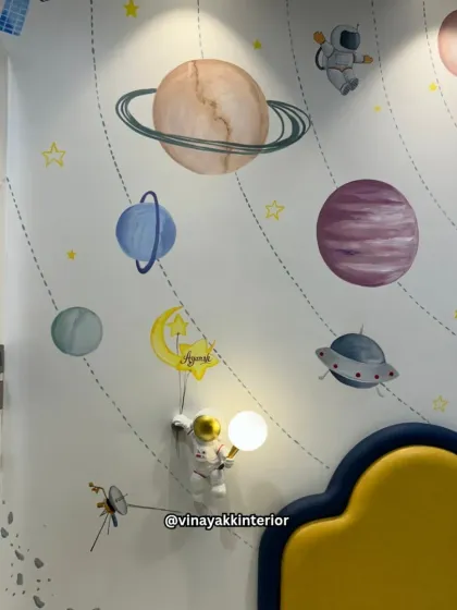 A close-up of the hand-painted solar system mural in this space-themed bedroom. The custom astronaut wall lamp, holding a glowing moon, adds a whimsical and functional touch, making learning about planets fun.