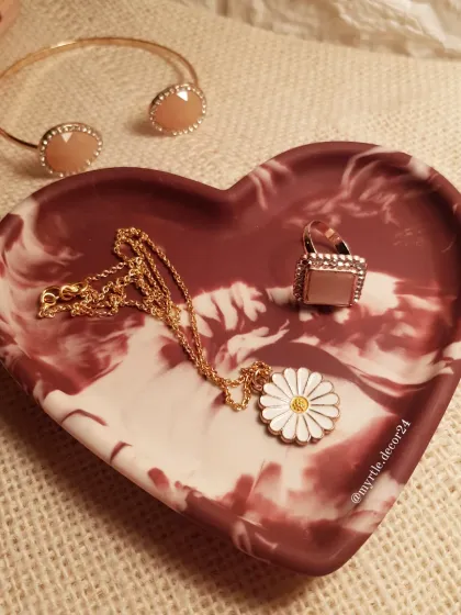 The Aurora Heart Tray styled with a daisy necklace and a statement ring, showing how it makes a beautiful backdrop for your jewelry.