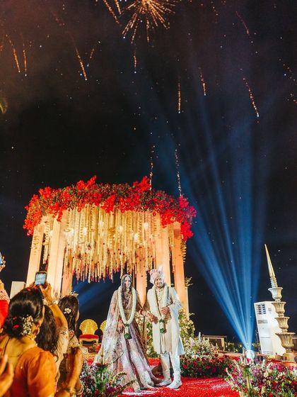 A picture-perfect Varmala. This shot captures the scale of the production, with dramatic uplighting, a beautifully decorated mandap, and a shower of fireworks to celebrate the couple's union.
