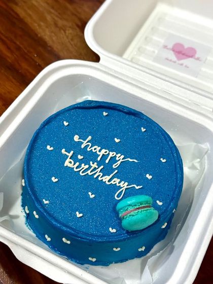 A chic and simple blue bento cake with 'happy birthday' in elegant script and a tiny, perfectly piped macaron. This shows how a minimalist design can be incredibly stylish.