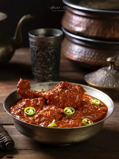 Hyderabadi Laal Chicken, a spicy red chicken curry. The styling for The Nawaab's uses rustic serveware to enhance the dish's traditional appeal.