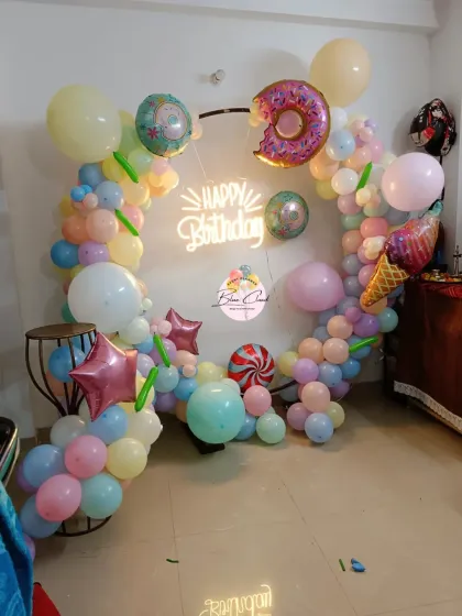 A sweet candy-themed birthday party with a pastel balloon ring and donut and ice cream foil balloons.
