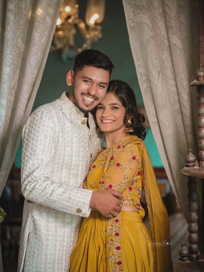 An intimate and joyful moment captured indoors. The couple's coordinated ethnic outfits in yellow and white add a bright and happy feel to this pre-wedding portrait.
