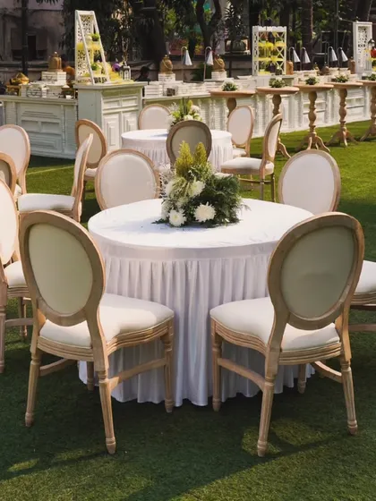 A classic and elegant outdoor seating arrangement with round tables and comfortable chairs, perfect for a garden party or daytime wedding reception.