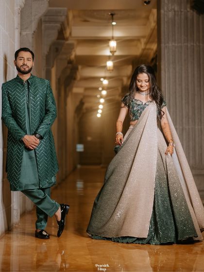 A stylish portrait of the couple in a grand corridor. Their confident poses and elegant outfits showcase their modern style.