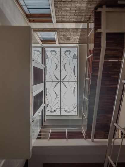Looking up through a central atrium towards a skylight with an elegant, artistic grill design. This feature serves as a focal point while drawing natural light deep into the home's interior.