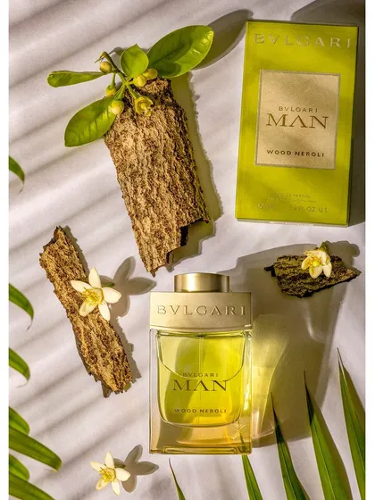 A still life product shoot for Bvlgari Man Wood Neroli perfume. The composition uses natural elements like wood bark and leaves, along with dramatic lighting, to evoke the fragrance's key notes.