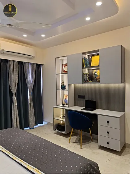 This is the son's bedroom from a recently delivered home in Ghaziabad. The design includes a sleek, built-in study unit with integrated lighting and overhead storage, creating a functional and stylish space for work and rest.