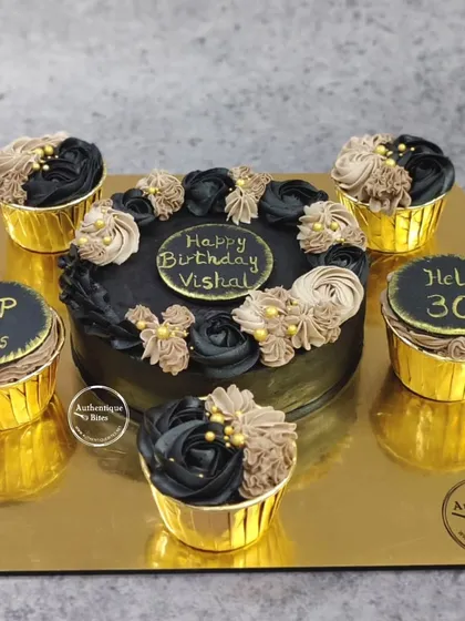 This glamorous black and gold cake and cupcake set was designed for a 30th birthday celebration. The combination allows for a central cutting cake while offering individual portions for guests, all unified by a sophisticated colour theme.
