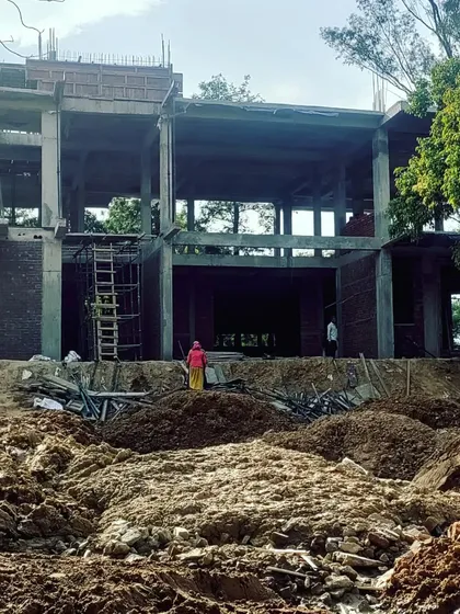 The structural frame of a farmhouse under construction, revealing the scale of the project and its open, double-height spaces. This stage shows the strong concrete foundation being built on excavated land, preparing for a home that will embrace the surrounding views.