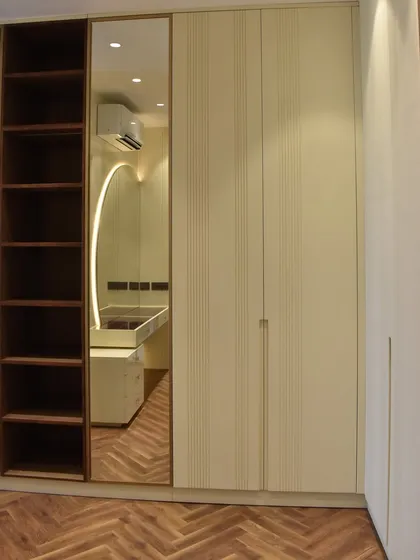 Here, a mirrored panel is seamlessly integrated with fluted PU-finished shutters. This design combines a full-length mirror with ample storage and a built-in dressing area.