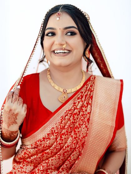 A happy, confident bride in her red saree, her makeup enhancing her beautiful smile.
