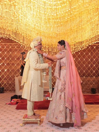 The Jaimala exchange under a canopy of shimmering golden strings. This indoor mandap design focused on creating a sense of grandeur and opulence, with light playing a key role in making the moment feel truly divine.