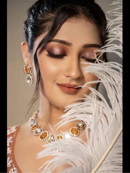 A similar artistic portrait, showing the bride's peaceful expression. The feather adds a touch of softness and creativity to this bridal beauty shot.