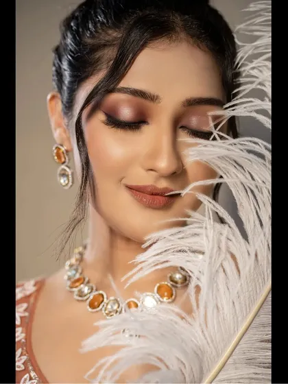 A similar artistic portrait, showing the bride's peaceful expression. The feather adds a touch of softness and creativity to this bridal beauty shot.