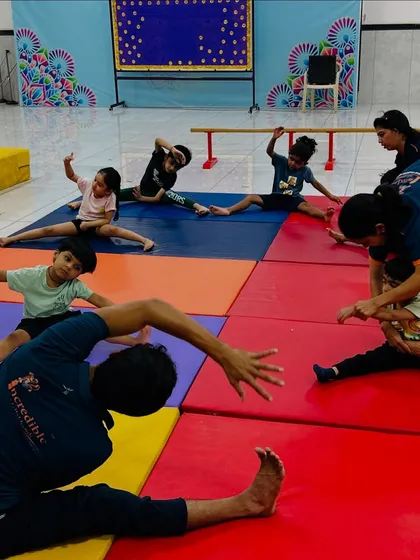 Flexibility is a cornerstone of gymnastics and Mallakhamb. Our coaches provide hands-on assistance to toddlers during stretching exercises, ensuring they learn proper form safely on our cushioned mats.