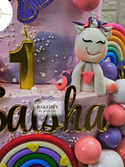 Another detailed shot of the unicorn first birthday cake, focusing on the cute fondant unicorn, the number '1' candle, and the rainbow accents.