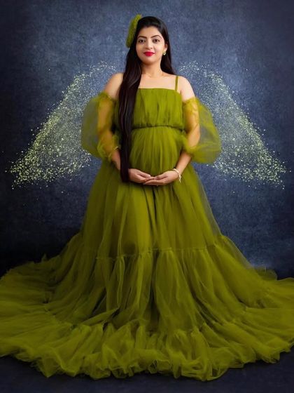 An angelic moment in a unique olive green. This tulle ball gown with delicate puff sleeves creates a dreamy and ethereal look, perfect for a memorable studio maternity session.