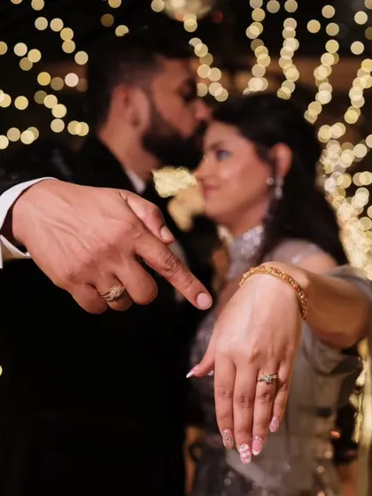 A creative and symbolic shot focusing on the engagement rings, with the couple sharing a tender moment in the beautifully blurred, bokeh-filled background.