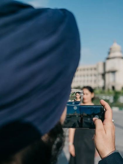 A creative shot capturing a photo within a photo, with Bangalore's Vidhana Soudha in the background. This meta-photograph is a playful way to document the pre-wedding shoot itself.