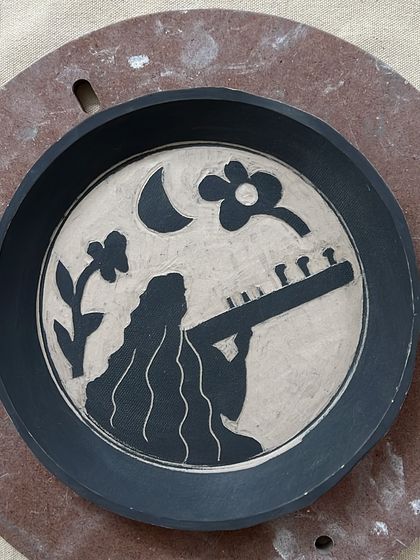 This hand-carved plate from a custom set represents a passion for music. The silhouette of a woman playing a sitar under the moon was designed to capture a specific mood and story, turning a simple plate into narrative art.