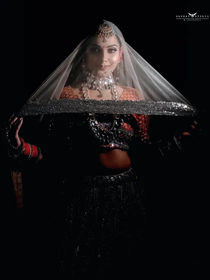 A dramatic low-key shot with the bride holding up her sequined veil, creating a striking silhouette.