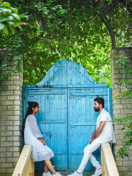 A couple poses on a bridge with a bright blue gate, a charming and colorful spot in our garden.