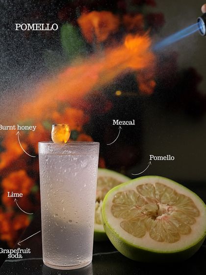 The Pomello cocktail, a fiery mix of burnt honey, mezcal, lime, and grapefruit soda. The blowtorch caramelizes the honey, adding a smoky depth to this refreshing drink.