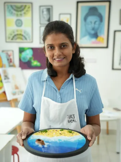 A participant holding her finished resin beach art. The details, from the sandy texture to the gentle waves, are all created using simple, guided techniques.