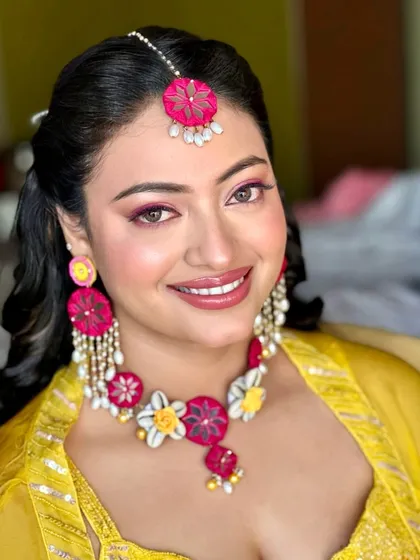 Haldi makeup should be bright, fresh, and long-lasting. For this bride, I used a vibrant pink on the eyes and lips to complement her yellow outfit and floral jewelry, creating a joyful and photogenic look for her daytime ceremony.