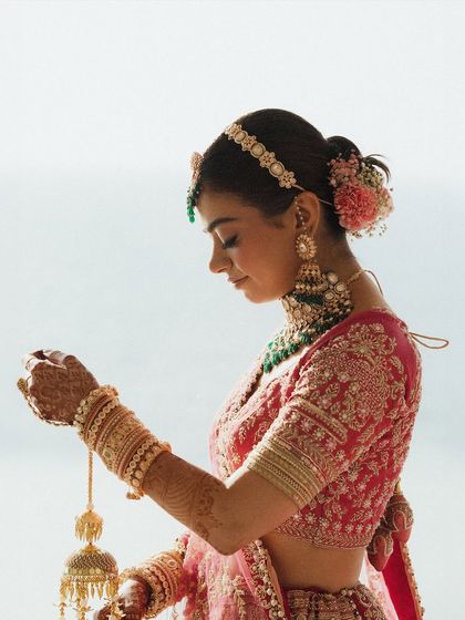 A beautiful profile shot of the bride, delicately holding her kaleeras against the backdrop of the sea. The soft light and her serene expression make this a timeless and elegant bridal portrait.
