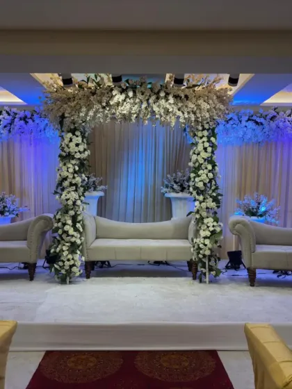 A pristine all-white stage decoration at Palm Beach banquet. The floral mandap structure and matching white sofas create a serene and heavenly atmosphere for a wedding ceremony.