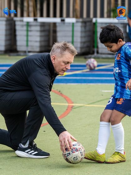 A moment of direct guidance. Heimir works one on one with a young player, demonstrating a fundamental skill. This hands on approach is central to our coaching method.