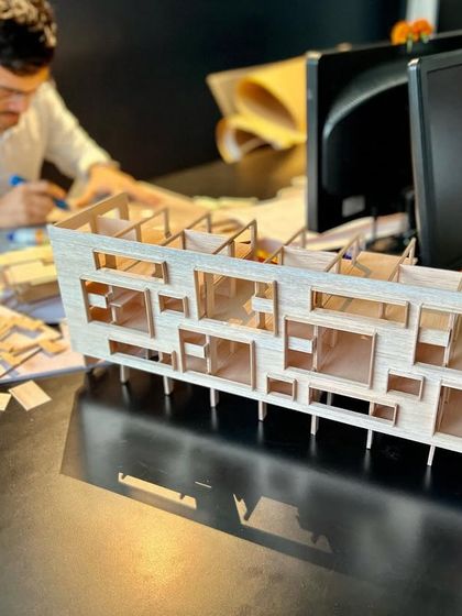 A team member works on the intricate balsa wood model of the "School at Navi Mumbai." This hands-on process is vital for refining the design and understanding its spatial qualities.