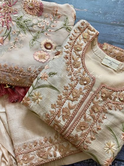 A flat-lay of the suit, showing the jacket-style neckline and the floral embroidery.