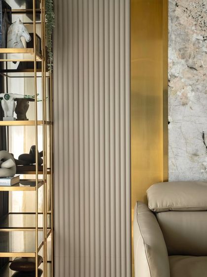 A detail shot of the den bedroom in the 'Urban Oasis' project. The image highlights the mix of textures, including fluted wall panels, brass accents, and abstract art pieces on the shelf.