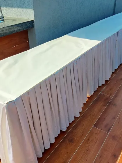 A simple and practical buffet table setup for a rooftop party. We provide a long table with clean white skirting, ready for the food service to be arranged.