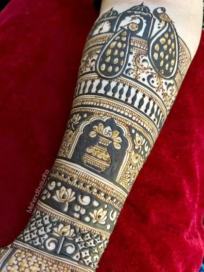 A close up on the forearm detail of a royal bridal design, highlighting the elegant peacock and kalash motifs created with bold, clean lines.