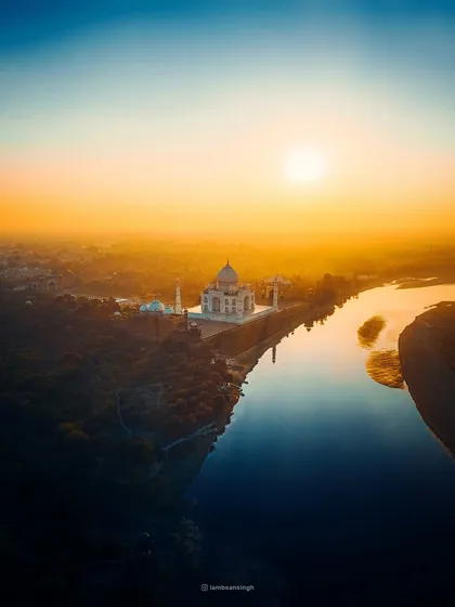 This drone shot of the Taj Mahal captures the brilliant golden light of the rising sun. The reflection in the river and the vast landscape give it an epic, painterly quality.