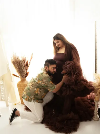 A tender moment captured. The father-to-be kneels to connect with the baby bump, a simple and heartfelt pose during their maternity session.