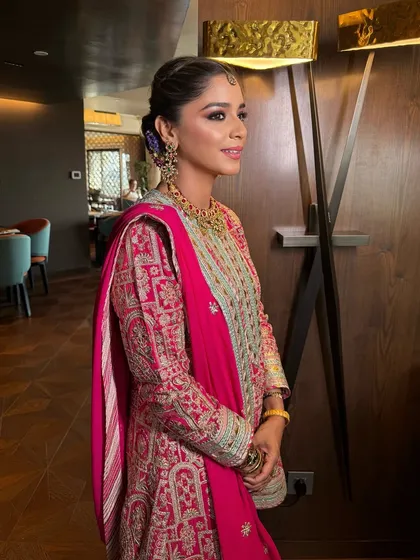 A side view of this elegant daytime look. The makeup is minimal and fresh, with a beautifully crafted floral bun as the centerpiece.