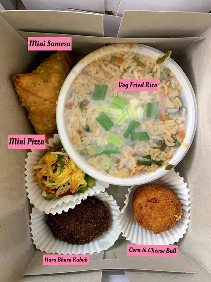 A single snack box with mini samosa, veg fried rice, mini pizza, hara bhara kabab, and a corn & cheese ball.