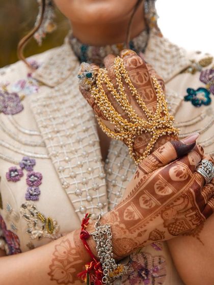 A detailed shot of a client's Mehendi accessories. The golden pearl hand harness sits beautifully over her intricate henna design, adding another layer of texture and elegance.