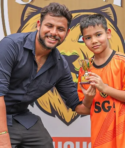 A young player proudly accepts his Player of the Match trophy, a memory that will inspire him for future games.