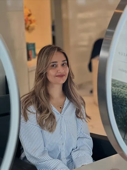 A beautiful mirror shot of the final beige blonde look. The color is soft, and the face-framing pieces brighten her complexion.